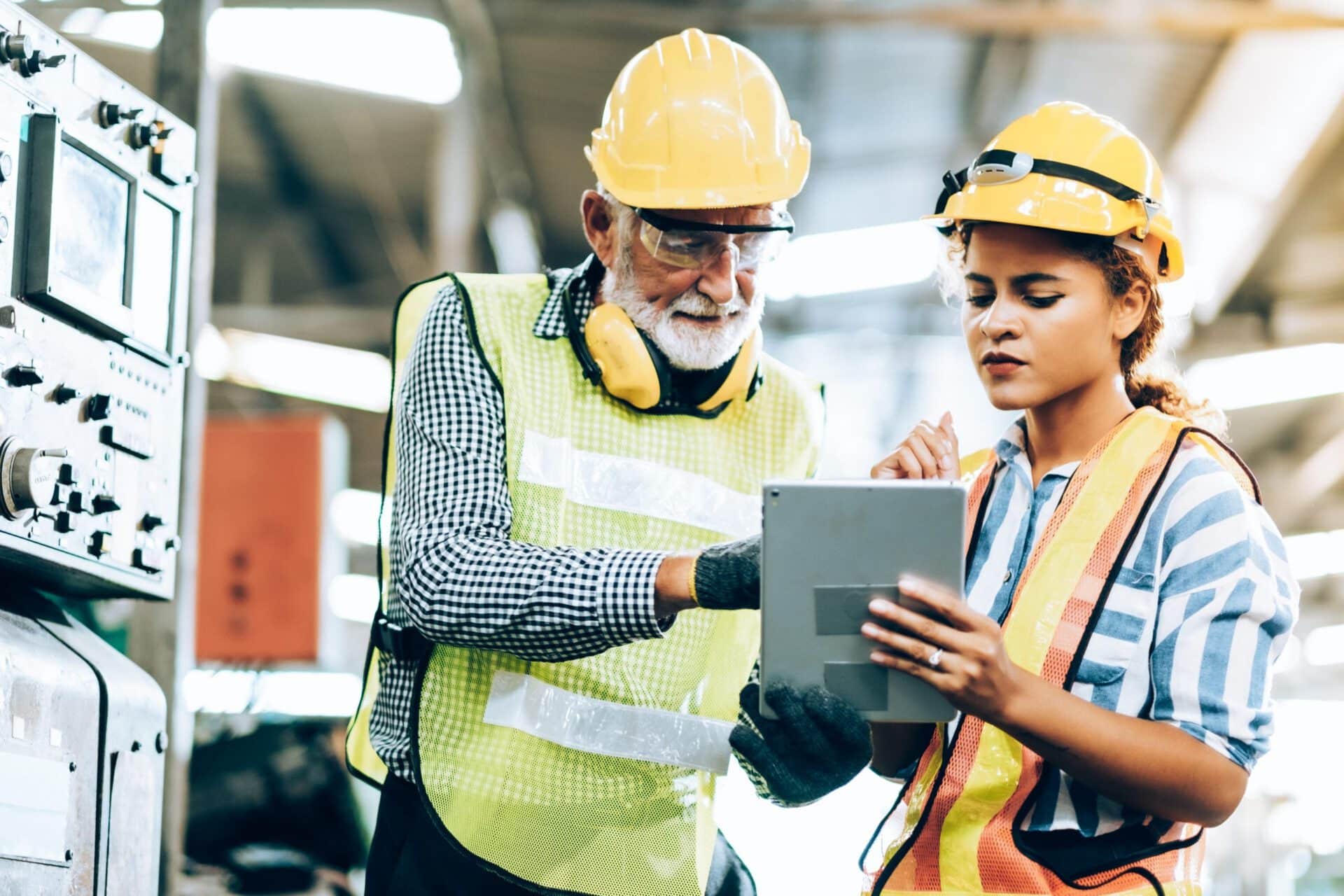 two factory workers looking at a tablet