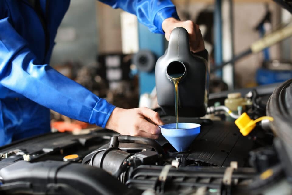 Male mechanic refilling car oil in service center