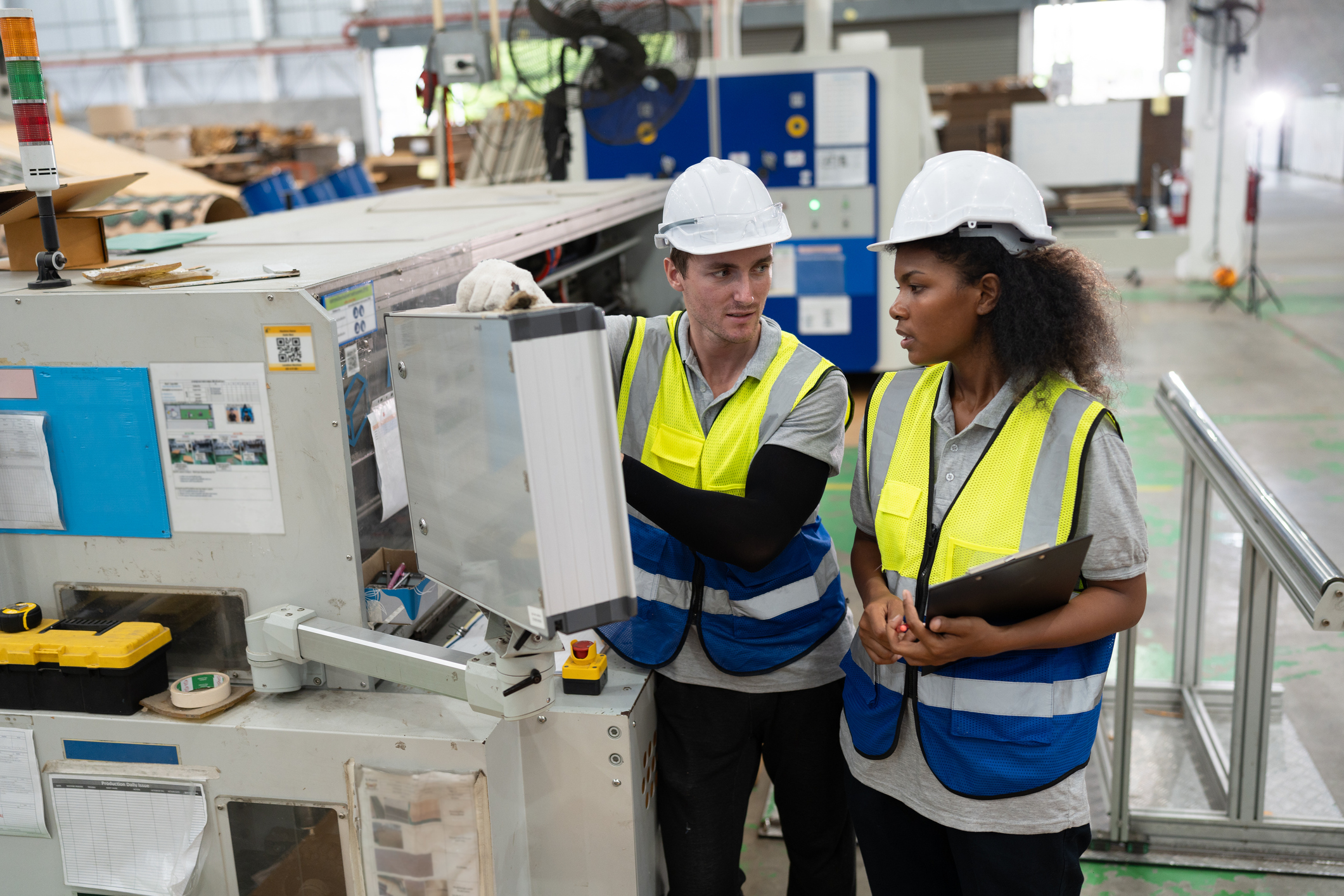 Portrait Caucasian businessman and African American businesswoman working and use monitor control machine at Kraft paper factory
